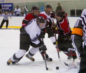 A BYU forward struggles for the puck against two Utah defenders in a game last season at Seven Peaks.