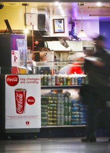 FILE - In this March 8, 2013, file photo, a Coca-Cola poster about the city's anticipated beverage ban is displayed at a pizza shop at New York's Penn Station. New York City's groundbreaking limit on the size of sugar-laden drinks has been struck down by a judge shortly before it was set to take effect. The restriction was supposed to start Tuesday, March 12, 2013. The rule prohibits selling non-diet soda and some other sugary beverages in containers bigger than 16 ounces. It applies at places ranging from pizzerias to sports stadiums, though not at supermarkets or convenience stores. (AP Photo/Bebeto Matthews)