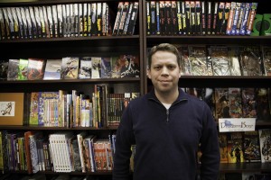 John Darowski stands next to bookshelves of comics at the Dragon's Keep in Provo. (Photo by Elliott Miller)