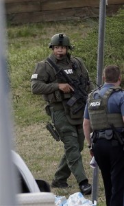 A police officer holds a rifle as he walks near the scene where a man is said to be holding four Gwinnett County firefighters hostage. (AP Photo)