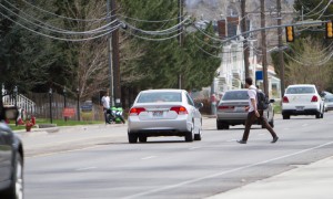 A student crosses the street into oncoming traffic on Ninth East, east of campus 