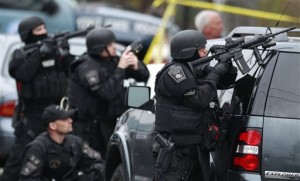Police in tactical gear surround an apartment building while looking for a suspect in the Boston Marathon bombings in Watertown, Mass., Friday, April 19, 2013. The bombs that blew up seconds apart near the finish line of the Boston Marathon left the streets spattered with blood and glass, and gaping questions of who chose to attack and why. (AP Photo/Charles Krupa)