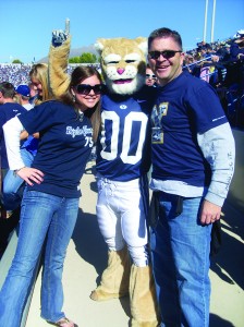 A BYU student and her father pose with Cosmo at a BYU football game. Courtesy BYU Alumni Association