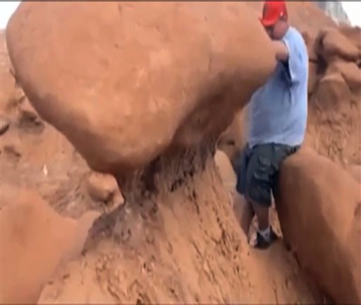 video taken by Dave Hall shows a Boy Scouts leader looking over an ancient Utah desert rock formation at Goblin Valley State Park, which he later knocked down. Authorities are mulling whether to press charges against and against the two men who cheered him on after they posted video of the incident online. AP photo by Dave Hall.