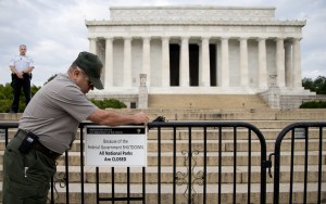 A US Park Police officer watches at left as a National Park Service employee posts a sign on a barricade closing access to the Lincoln Memorial in Washington, Tuesday, Oct. 1, 2013. 