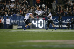Taysom Hill jumps with the ball in attempt to leap over two Boise State defenders.