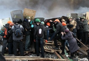 Anti-government protesters protected themselves with shields during clashes with riot police in Kiev's Independence Square, the epicenter of the country's current unrest (Photo Courtesy Associated Press).