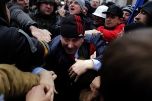 A suspected supporter of Ukraine's embattled president Viktor Yanukovych, center, is assaulted by anti-government protesters in Kiev, Ukraine (Photo courtesy Associated Press). 