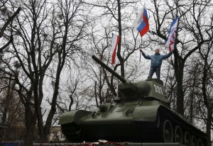 A Pro-Russian demonstrator waves Russian and Crimea flags from an old Soviet Army tank during a protest in front of a local government building in Simferopol, Crimea, Ukraine, Thursday, Feb. 27, 2014. Ukraine's acting interior minister says Interior Ministry troops and police have been put on high alert after dozens of men seized local government and legislature buildings in the Crimea region. The intruders raised a Russian flag over the parliament building in the regional capital, Simferopol, but didn't immediately voice any demands. (AP Photo)
