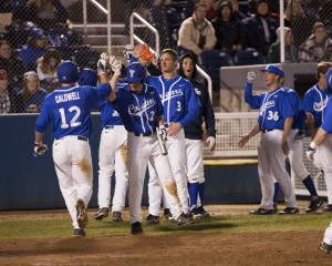 Players celebrate after Kelton Caldwell scores a run for BYU. Caldwell tied the school's record for two triples in a single game. Photo by Elliott Miller