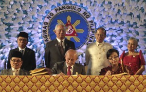In this handout photo released by the Malacanang Photo Bureau, President Benigno S. Aquino III, second from right standing, looks beside, from left, Moro Islamic Liberation Front (MILF) Chairman, Al Haj Murad Ebrahim, Malaysian Prime Minister Najib Razak, and Secretary Teresita Quintos-Deles, Presidential Adviser on the Peace Process, as they witness the signing of the Comprehensive Agreement on the Bangsamoro (CAB) by MILF chief negotiator Mohagher Iqbal, Datu Tengku Gnafar and Miriam Coronel Ferrer of the Philippine government in a ceremony at the Malacanang Presidential Palace (Photo Courtesy Associated Press).