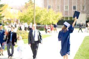 An April graduate celebrates her accomplishment  by holding her diploma in the air. (Photo by cberryphotos)