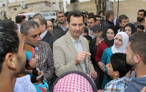 In this photo taken on Sunday, April 20, 2014 and released by the Syrian official news agency SANA, Syrian President Bashar Assad, center, speaks with Syrian citizens during his visit to Ain al-Tineh village (Photo courtesy Associated Press). 