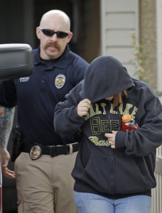 In this photo taken on Tuesday, Aug. 26, 2014, Alicia Marie Englert shields her face as she is escorted by police from a home in Kearns, Utah. Charging documents show Englert, a accused of dumping her newborn in a neighbour's trash, that she was afraid to tell her parents about the pregnancy. She was arrested Tuesday night on suspicion of attempted murder. The baby girl was in critical condition.  (AP Photo/Rick Bowmer)