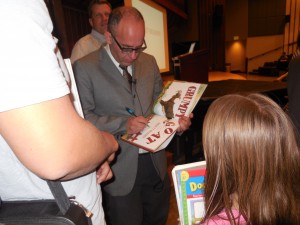 Bret Helquist, illustrator and artist, signs 9-year-old Natalie Baker's book in the Madsen Recital Hall of the HFAC. Helquist was one of many Alumni guests in the Homecoming Lecture Series. (Bret Mortimer) 
