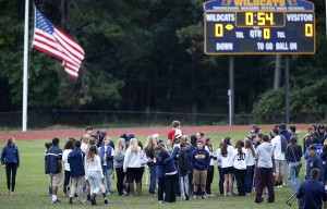 People walk on the football field at Shoreham Wading River High School in Shoreham, N.Y., Thursday, Oct. 2, 2014, after a vigil for 16-year-old varsity football player Tom Cutinella, who died Wednesday night after a fatal football collision at an away game . (AP Photo/Kathy Willens)