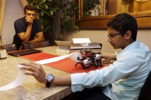 Shubham Banerjee works on his Lego robotics braille printer as his dad Neil watches at home. Banerjee launched a company to develop a low-cost machine to print Braille materials for the blind. It's based on a prototype he built with his Lego robotics kit for a school science fair project. (AP Photo/Marcio Jose Sanchez)