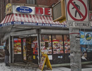 A woman approaches a deli where a robbery occurred, shortly before police and suspects exchanged shots, Tuesday, Jan. 6, 2015, in New York. (AP Photo/Bebeto Matthews)