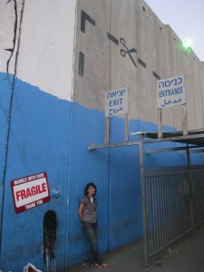 Sahar Qumsiyeh stands next to the Israeli separation wall in the West Bank. (Sahar Qumsiyeh)