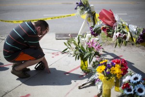 Noah Nicolaisen, of Charleston, S.C., kneels at a makeshift memorial down the street from where a white man opened fire Wednesday night during a prayer meeting inside the Emanuel AME Church killing several people in Charleston, Thursday, June 18, 2015. (AP Photo/David Goldman)