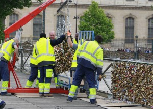 Paris city employees remove a railing loaded with locks on the famed Pont des Arts bridge in Paris, Monday June 1, 2015. Lovers in Paris, beware: City authorities are taking down thousands of padlocks affixed to the famed Pont des Arts bridge. The city council says the locks, usually hung by couples to express eternal love, cause long-term damage to Paris heritage and sometimes pose a security risk. Last summer a chunk of fencing fell off under their weight. (AP Photo/Remy de la Mauviniere)
