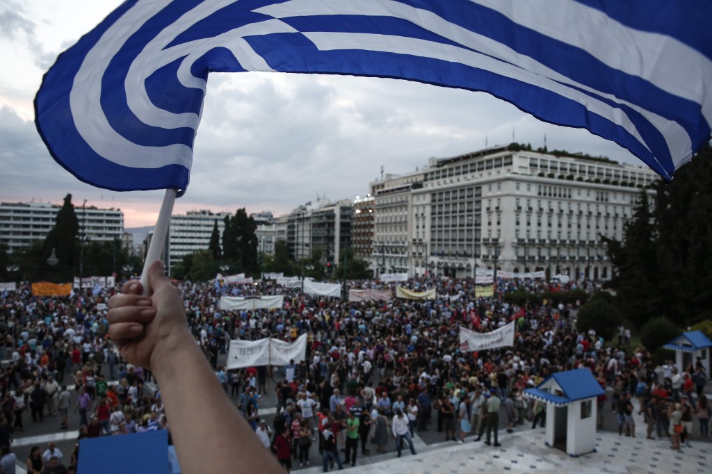 An anti-austerity protester waves a Greek flag during a rally in front of the parliament in Athens, Greece, on Sunday, June 21, 2015. A day ahead of a crucial emergency eurozone summit, European leaders renewed efforts to reach a deal between Greece and its creditors that would allow the debt-ridden country to avoid a default and a potentially disastrous exit from the euro. (AP Photo/Yorgos Karahalis)