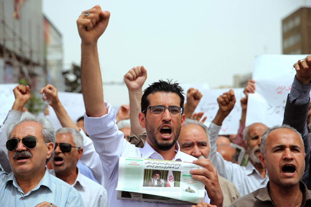 A group of Iranian worshippers chant slogans in a demonstration over negotiations with world powers on Iran's nuclear program, after their Friday prayer, in Tehran, Iran, Friday, May 29, 2015. U.S. Secretary of State John Kerry will meet with Iranian Foreign Minister Mohammad Javad Zarif in Geneva on Saturday in an effort to move the nuclear talks forward ahead of a June 30 target date for a deal. Newspaper shows an image and quote from the late Iranian revolutionary founder Ayatollah Khomeini. (AP Photo/Ebrahim Noroozi)