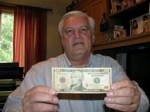 In this photo taken July 8, 2015, in Columbus, Ohio, Doug Hamilton holds a $10 bill bearing the portrait of his direct ancestor, Alexander Hamilton. Doug Hamilton and others are trying to persuade the U.S. Treasury Department to change its plan to alter the bill as part of the effort to include a portrait of a woman on paper money. (AP Photo/Mitch Stacy)