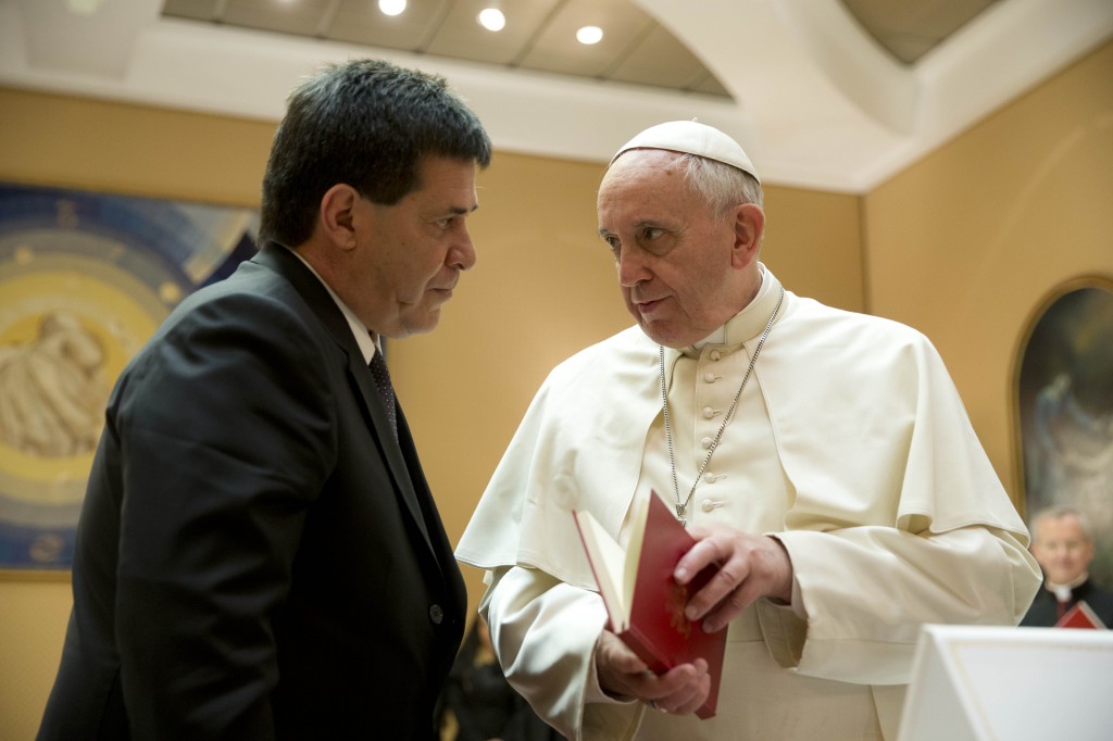 FILE - In this April 29, 2014 file photo, Pope Francis presents Paraguay's President Horacio Cartes with the book of the gospel during a private audience at the Vatican. Pope Francis is taking his "church for the poor" to three of South America's poorest and most peripheral countries, making a grueling, week-long trip that will showcase the pope at his unpredictable best: speaking his native Spanish on his home turf about issues closest to his heart. (AP Photo/Gregorio Borgia, Pool, File)