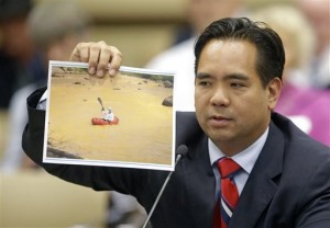 Utah Attorney General Sean Reyes holds a photograph from the massive spill from the abandoned Colorado gold mine that sent toxic wastewater flowing into Utah and at least two other states during the State Water Development Commission meeting Tuesday, Aug. 18, 2015, in Salt Lake City. (AP Photo/Rick Bowmer)