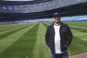 Kirk McKnight stands on the field at Yankee Stadium.  "The Voices of Baseball" showcases 30 modern baseball stadiums as well as 30 from the past.  (Courtesy Kirk McKnight)