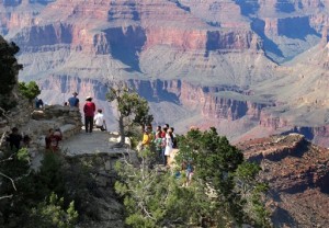 In this Wednesday, Aug. 19, 2015 photo, visitors gather at an outlook on the South Rim of Grand Canyon National Park in northern Arizona. The Grand Canyon and other big national parks are seeing more visitors than usual this year, partly driven by good weather, cheap gas and marketing campaigns. (AP Photo/Felicia Fonseca)