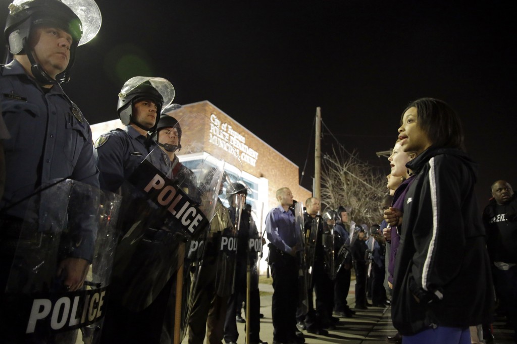 FILE - In this March 11, 2015, file photo, police and protesters square off outside the Ferguson Police Department, in Ferguson, Mo. Ferguson's new municipal judge Donald McCullin ordered massive changes Monday, Aug. 24, in the city's much-criticized municipal court, a move he said is aimed at restoring confidence in the system and easing the burden on needy defendants. The changes come after a critical U.S. Department of Justice report cited racial profiling among Ferguson police and a municipal court system that often targeted blacks. (AP Photo/Jeff Roberson, File)