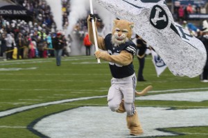 Cosmo leads the football team out on the field waving the BYU flag. Cosmo is currently Utah valley's superhero and protector. (BYU Athletic Marketing)