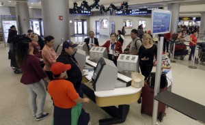 CORRECTS YEAR OF PHOTO WAS TAKEN TO 2014 INSTEAD OF 2015 - FILE - In this Nov. 25, 2014 file photo, travelers check in their luggage as they prepare to travel at Miami International Airport in Miami. A stronger economy and lower gas prices means Thanksgiving travelers can expect more highway congestions in 2015. Airlines for America, the lobbying group for several major airlines, forecasts 25.3 million passengers will fly on U.S. airlines, up 3 percent from last year. (AP Photo/Alan Diaz, File)