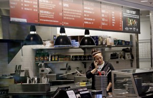 A woman talks on the phone as she stands in the kitchen area of a closed Chipotle restaurant, Monday, Nov. 2, 2015, in Seattle. An E. coli outbreak linked to Chipotle restaurants in Washington state and Oregon has sickened nearly two dozen people in the third outbreak of foodborne illness at the popular chain this year. Cases of the bacterial illness were traced to six of the fast-casual Mexican food restaurants, but the company voluntarily closed down 43 of its locations in the two states as a precaution. (AP Photo/Elaine Thompson)