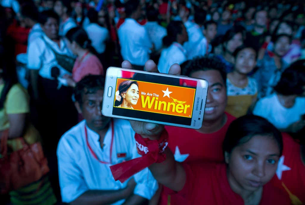 A supporter of Myanmar's National League for Democracy party displays her mobile phone with a picture of Suu Kyi as they gather to celebrate unofficial election results outside the NLD headquarters in Yangon, Myanmar, Monday, Nov. 9, 2015. Opposition leader Aung San Suu Kyi's NLD party said Monday that it was confident it was headed for a landslide victory in Myanmar's historic elections, and official results from the government that began trickling in appeared to back up the claim. (AP Photo/Gemunu Amarasinghe)