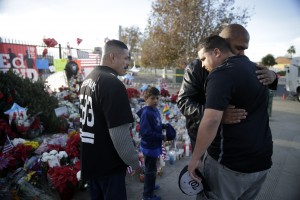 Mourners comfort each other at a makeshift memorial site honoring Wednesday's shooting victims Monday, Dec. 7, 2015 in San Bernardino, Calif. Thousands of employees of San Bernardino County are preparing to return to work Monday, five days after a county restaurant inspector and his wife opened fire on a gathering of his co-workers, killing 14 people and wounding 21. (AP Photo/Jae C. Hong)