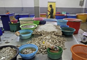 In this Monday, Nov. 9, 2015 photo, shrimp are left on an abandoned peeling table as a Thai soldier walks past during a raid on the shrimp shed in Samut Sakhon, Thailand. In November 2015, AP journalists followed and filmed trucks loaded with freshly peeled shrimp going from this shed to major Thai exporting companies, and then tracked it globally. They also traced similar connections from another factory raided six months earlier and interviewed more than two dozen workers from both sites. The shrimp made its way into the supply chains of major food stores and retailers in all 50 U.S. states. (AP Photo/Dita Alangkara)