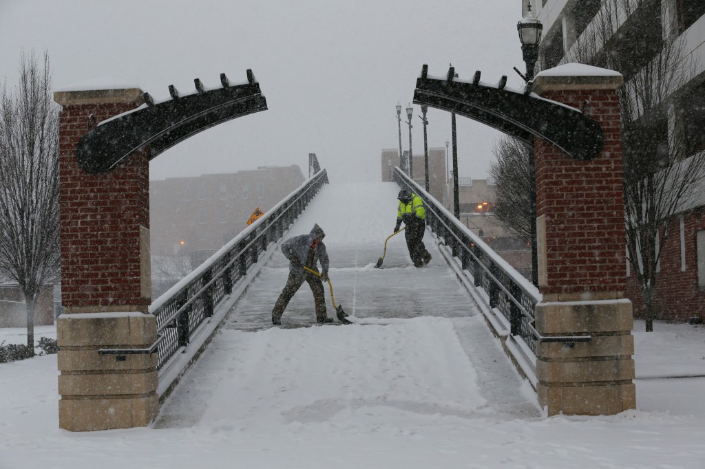 Kenny Hamblin, left, and Andrew Watts with the Roanoke Parks and Recreation Department shovel snow on the Martin Luther King bridge on First Street and Salem Avenue as snow falls Friday morning, Jan. 22, 2016, in Roanoke, Va. A blizzard menacing the Eastern United States started dumping snow in Virginia, Tennessee and other parts of the South on Friday as millions of people in the storm's path prepared for icy roads, possible power outages and other treacherous conditions. (Stephanie Klein-Davis/The Roanoke Times via AP) LOCAL TELEVISION OUT; SALEM TIMES REGISTER OUT; FINCASTLE HERALD OUT; CHRISTIANBURG NEWS MESSENGER OUT; RADFORD NEWS JOURNAL OUT; ROANOKE STAR SENTINEL OUT; MANDATORY CREDIT