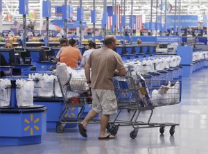 In this Thursday, June 4, 2015, photo, shoppers walk from the checkout at a Wal-Mart Supercenter store in Springdale, Ark. Wal-Mart announced Friday, Jan. 15, 2016, that it is closing 269 stores, more than half of them in the U.S. and another big chunk in its challenging Brazilian market. The store closures will start at the end of January. (AP Photo/Danny Johnston)