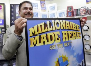 Balbir Atwal, the owner of a 7-Eleven store that sold a winning Powerball lottery ticket, holds up a Millionaire Made Here, sign at his store in Chino Hills, Calif., Thursday, Jan. 14, 2016. Atwal, says he was at home when a friend called to tell him that someone in Chino Hills had hit the jackpot. Atwal says he didn't know the ticket was purchased at his store until he turned on the TV. (AP Photo/Nick Ut)