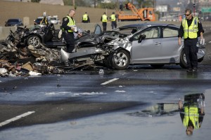 California Highway Patrol officers investigate a fiery crash involving multiple vehicles on Saturday, Feb. 27, 2016 in Commerce, Calif. Distracted driving significantly increases the risk of a crash. (Irfan Khan/Los Angeles Times via AP)