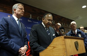 CORRECTS ID OF MAN AT RIGHT TO NYPD CHIEF OF DETECTIVES ROBERT BOYCE, NOT JAMES O'NEILL - New York City Mayor Bill de Blasio listens as New York City Police First Deputy Commissioner Benjamin Tucker speaks at a hastily called press conference at Lincoln Hospital, Thursday, Feb. 4, 2016, in the Bronx borough of New York after two New York City police officers were shot in a public housing complex int he Bronx by an armed suspect who apparently turned the weapon on himself not far from where de Blasio was delivering his state of the city address Thursday evening. New York City Police Department Chief of Detectives Robert Boyce, listens, right. (AP Photo/Kathy Willens)