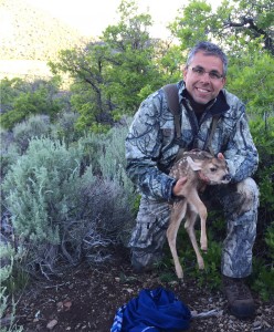 Brock McMillan, Department Chair of Plant and Wildlife Sciences, says deer populations in Utah have risen in recent years. Here, he holds with a fawn mule deer on a research trip studying the survival of neonate mule deer. (Brock McMillan)