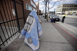 A person covered in a blanket walks along a street Monday, Feb. 29, 2016, in Salt Lake City. Utah lawmakers are set to consider a proposal to spend $27 million to build new shelters and renovate old ones, something that homeless advocates say would relieve the strain on facilities concentrated in that downtown area. (AP Photo/Rick Bowmer)