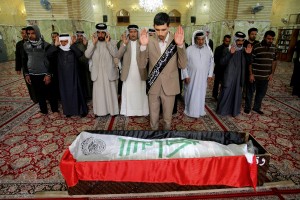 Mourners pray over an Iraqi flag-draped coffin of bomb victim, Rasul Kadim, 24, during his funeral procession at the holy shrine of Imam Ali in Najaf, 100 miles (160 kilometers) south of Baghdad, Iraq, Monday, March 7, 2016. The suicide bomber on Sunday rammed his explosives-laden fuel truck into a security checkpoint south of Baghdad, killing and wounding dozens, officials said, the latest episode in an uptick in violence in the war-ravaged country. The Islamic State group claimed responsibility for the suicide bombing in an online statement. (AP Photo/Anmar Khalil)