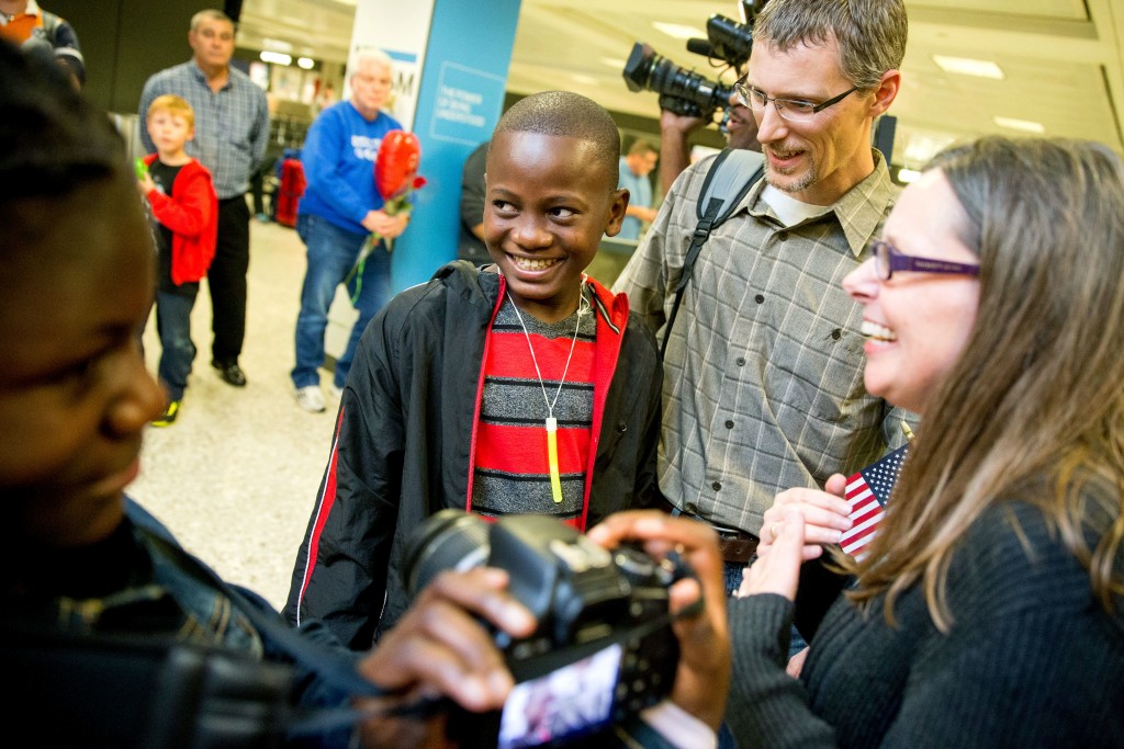 In this Nov. 11, 2015 photo, Jennifer and Eric Sands of Illinois, right, accompanied by their adopted daughter Joy, 12, left, smile as their adopted son Issaac, 12, center arrives from Congo at Dulles International Airport, in Dulles, Va. The number of foreign children adopted by U.S. parents dropped by 12 percent last year to the lowest level since 1981, according to new State Department figures. 