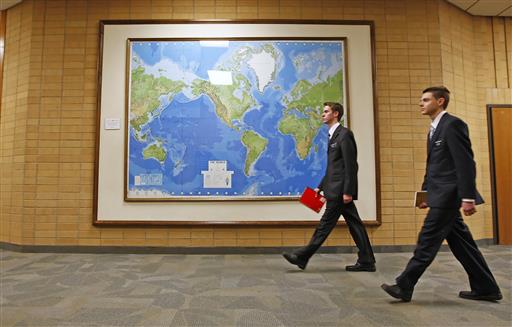 In this Jan. 31, 2008, file photo, two Mormon missionaries walk past a large map of the world in a hallway at the Missionary Training Center in Provo, Utah. Mormon missionaries will remain in Russia despite the country's new anti-terrorism law, which will put greater restrictions on religious work starting later this month. In a statement issued Friday, July 8, 2016, the Church of Jesus Christ of Latter-day Saints said that missionaries will respect a measure that Russian President Vladimir Putin signed into law this week. (AP Photo/George Frey, File)