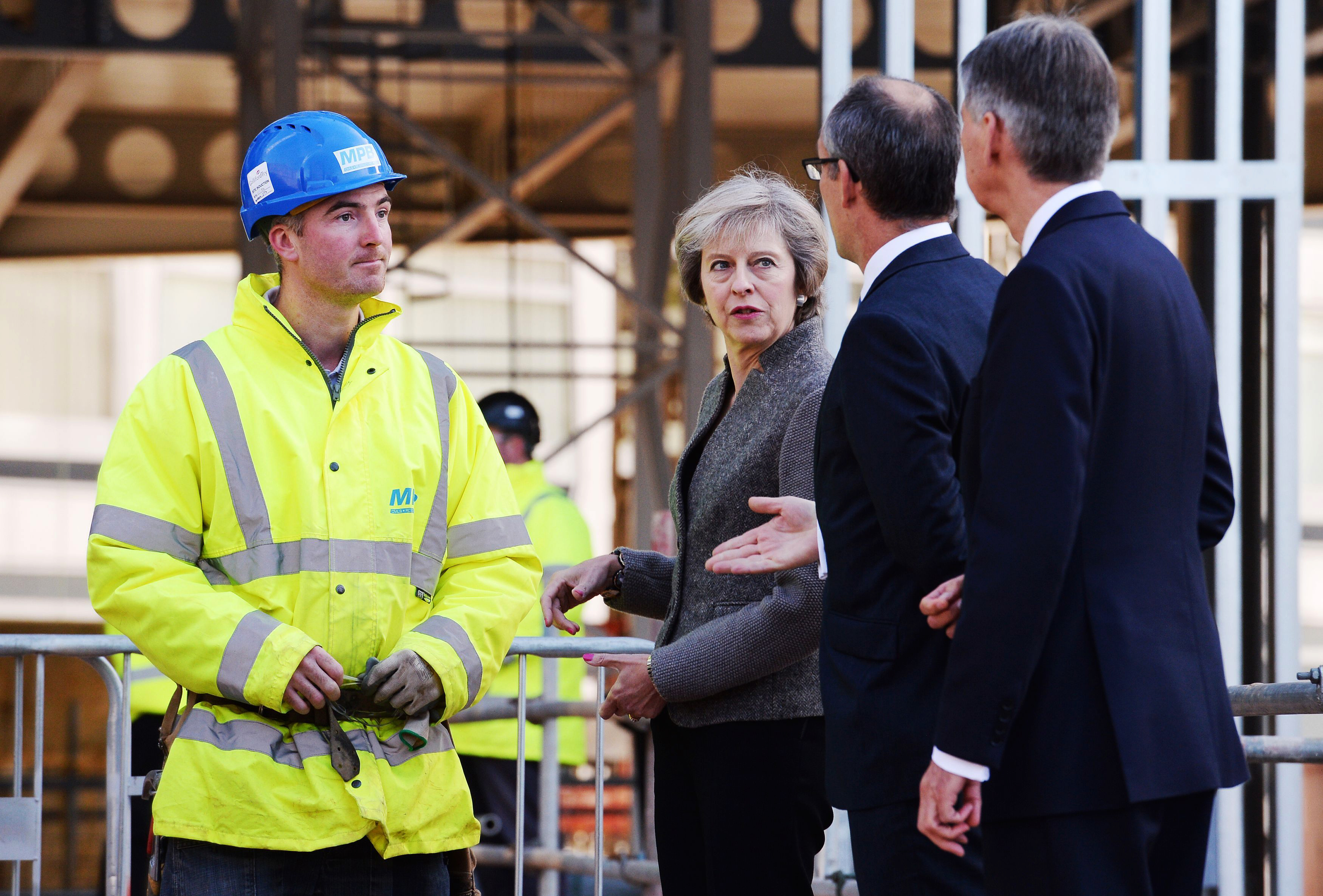 Britain's Prime Minister Theresa May and Chancellor of the Exchequer Philip Hammond, right, during a visit to a construction site in Birmingham, England, where new HSBC bank offices are being built, Monday Oct. 3, 2016. May announced Sunday a timetable for Britain's exit from the European Union, and Treasury chief Hammond warned on Monday of turbulence in the coming years as Britain negotiates its exit from the trading bloc. (Stefan Rousseau / PA via AP)